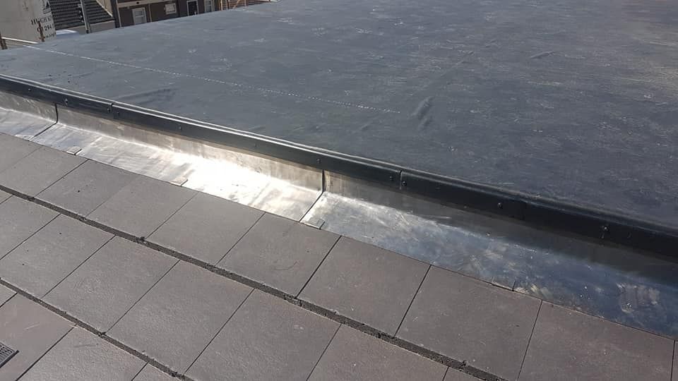 A black EPDM rubber flat roof edged with lead trim.