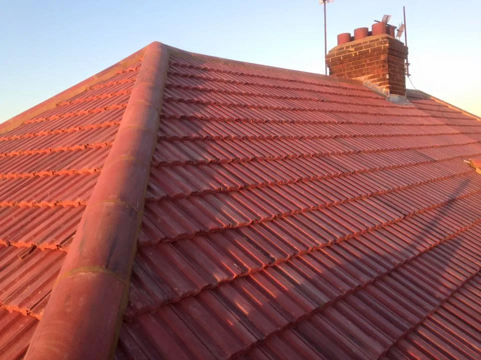 A roofer carrying out chimney repair work on a pitched tile roof. A roofer carrying out chimney repair work on a pitched tile roof.