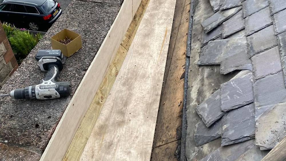 A chimney stack undergoing repair with a roofing sheet laid across the tiles. A chimney stack undergoing repair with a roofing sheet laid across the tiles.