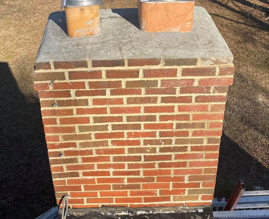 Close-up of a brick chimney stack with repointed mortar joints on a tiled roof. Close-up of a brick chimney stack with repointed mortar joints on a tiled roof.