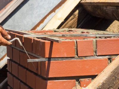 A brick chimney stack on a sloped tile roof after repair and repointing work. A brick chimney stack on a sloped tile roof after repair and repointing work.