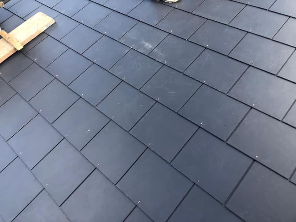 A close-up of new grey slate roof tiles, an example of durable roofing materials. A close-up of new grey slate roof tiles, an example of durable roofing materials.