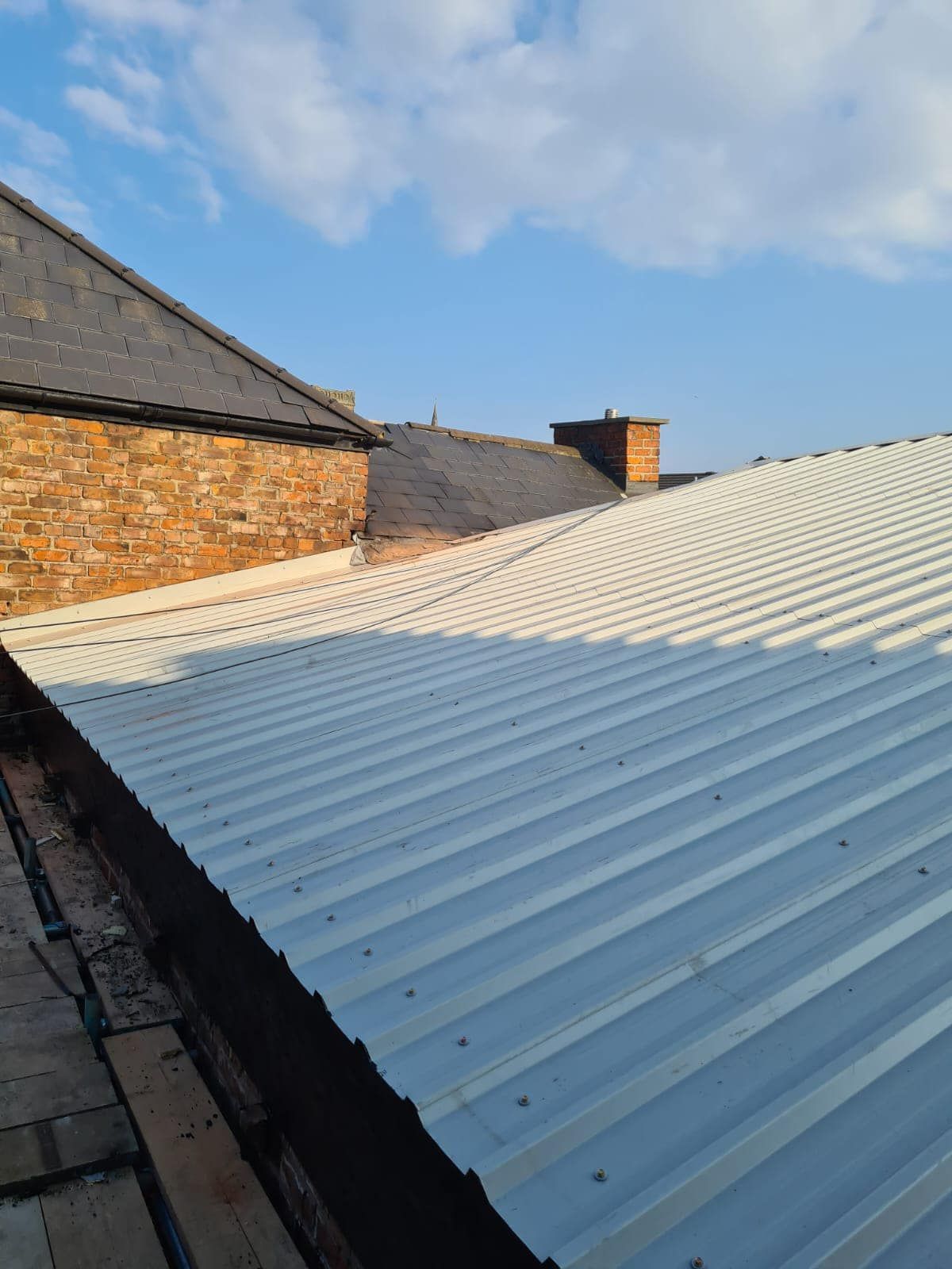 A corrugated metal roof with a brick chimney stack.
