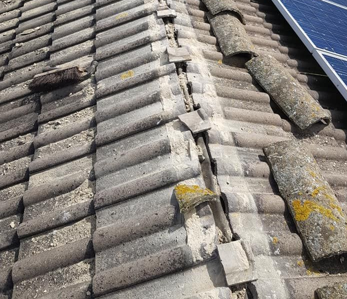 Cracked ridge tiles with the old mortar bedding exposed and crumbling. Cracked ridge tiles with the old mortar bedding exposed and crumbling.