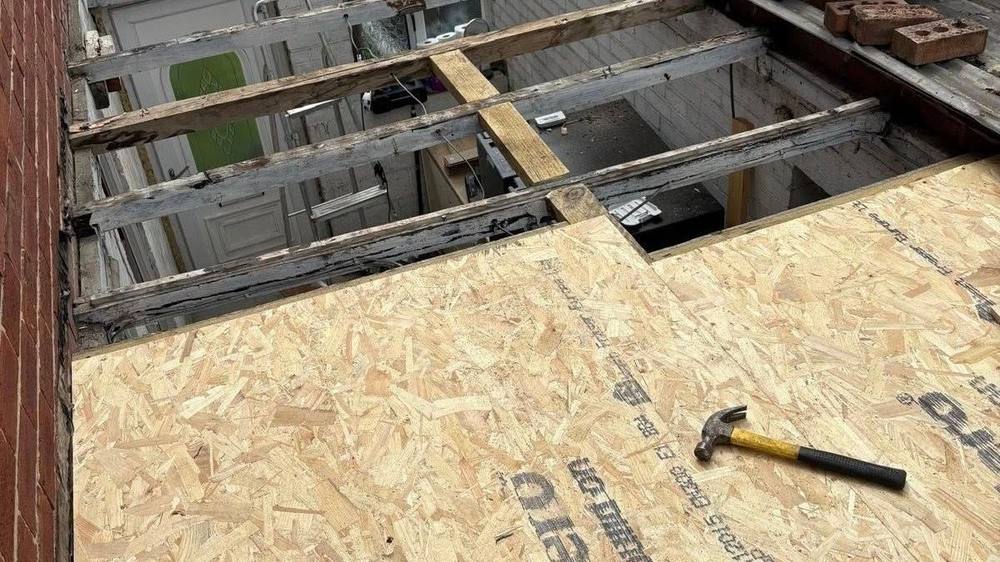 Exposed roof joists and OSB board with a hammer, showing the structure water can damage behind a leak.