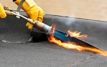 Close-up of a roofer using a gas torch to heat and bond felt roofing membrane during a flat roof repair.