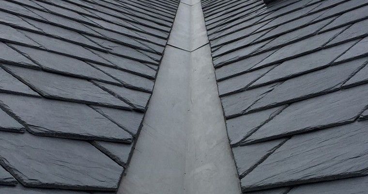 A metal roof valley running between two tiled roof slopes on a residential property. A metal roof valley running between two tiled roof slopes on a residential property.