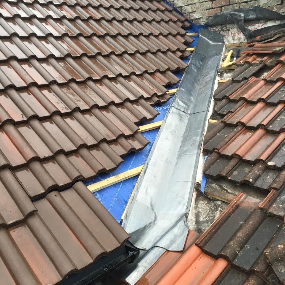 New lead valley flashing between red tile roofs, checked as part of a roof survey.