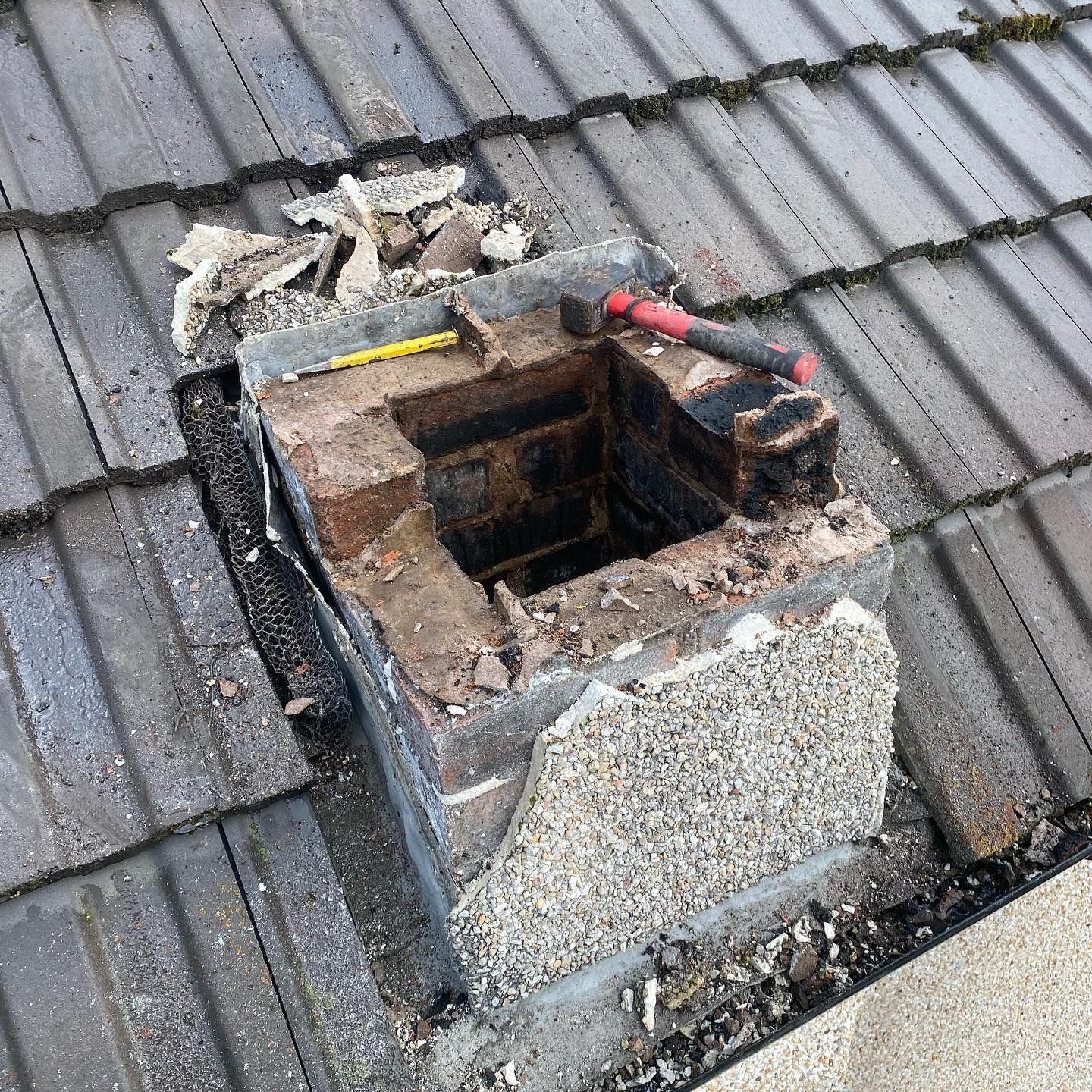 An open chimney stack with a hammer and rubble showing structural repair work in progress An open chimney stack with a hammer and rubble showing structural repair work in progress