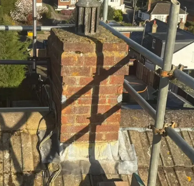 A rebuilt brick chimney stack surrounded by scaffolding during roofing work. A rebuilt brick chimney stack surrounded by scaffolding during roofing work.