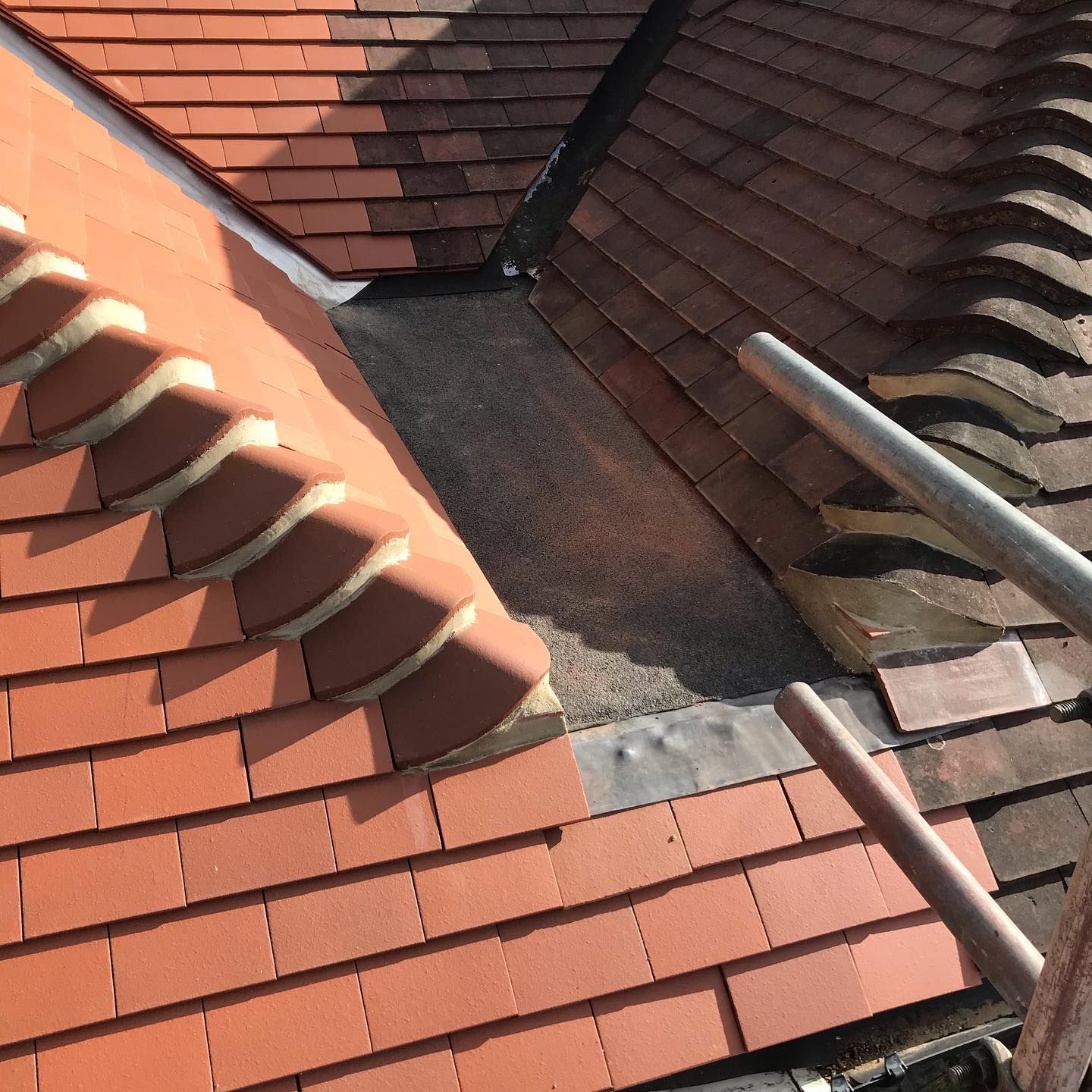 A red clay tile roof valley with lead flashing, the kind of detail storms can lift or crack. A red clay tile roof valley with lead flashing, the kind of detail storms can lift or crack.