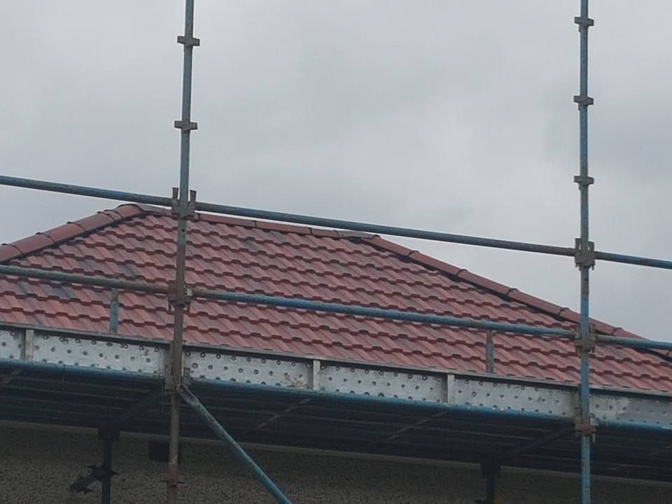A red tiled roof and chimney stack enclosed in full scaffolding. A red tiled roof and chimney stack enclosed in full scaffolding.