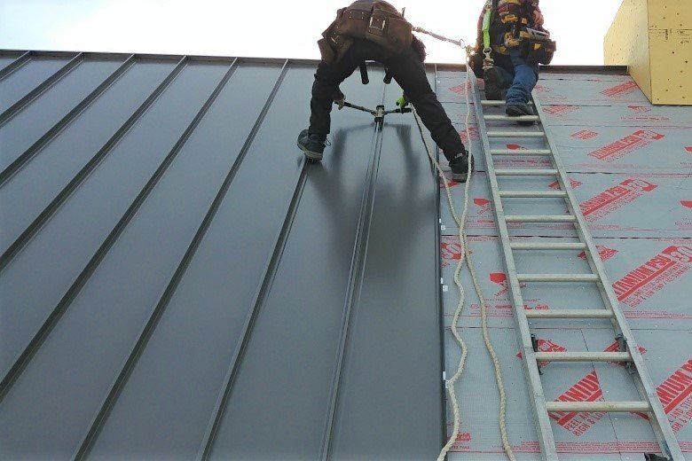 A harnessed roofer working safely on a grey metal roof, backed by checkable CSCS and IOSH credentials.