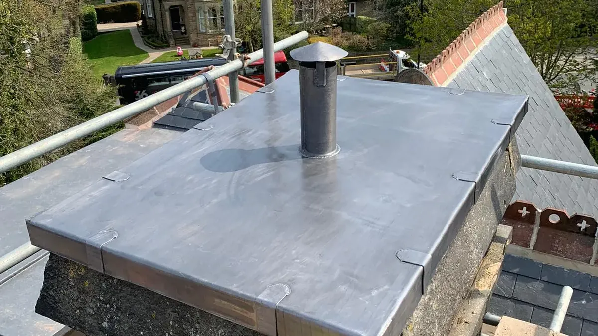 A roofer on a ladder carrying out chimney repair work against a tiled roof. A roofer on a ladder carrying out chimney repair work against a tiled roof.