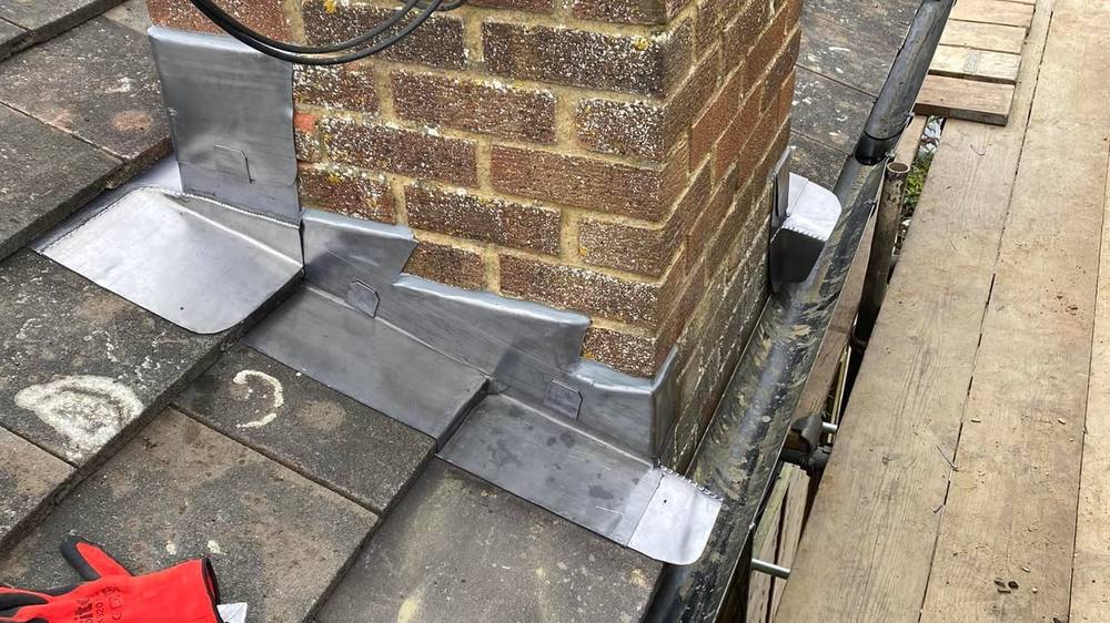 Lead flashing and satellite dish fitted around a brick chimney stack on a Nottingham roof Lead flashing and satellite dish fitted around a brick chimney stack on a Nottingham roof