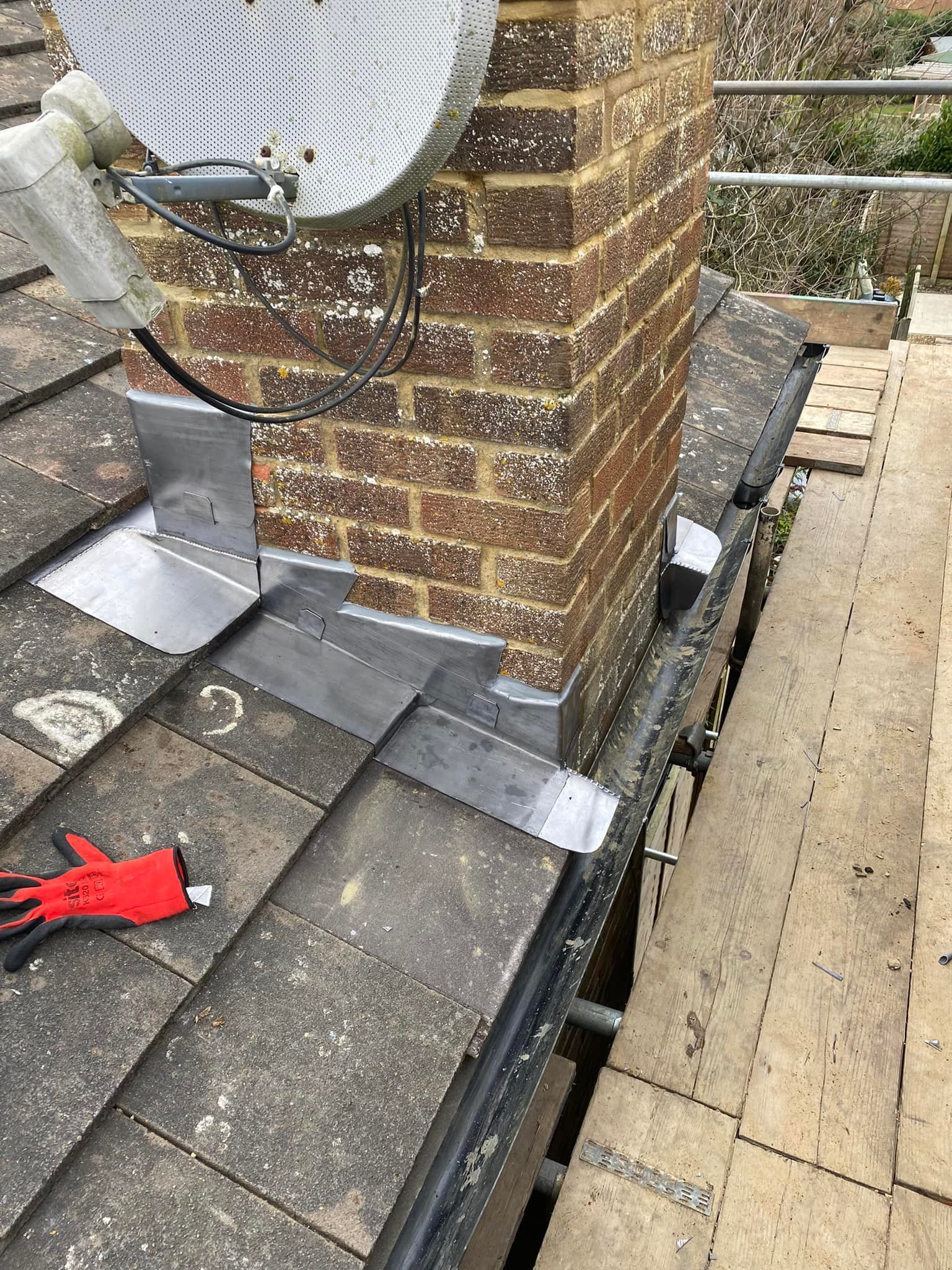 A satellite dish mounted beside new lead flashing on a brick chimney stack. A satellite dish mounted beside new lead flashing on a brick chimney stack.