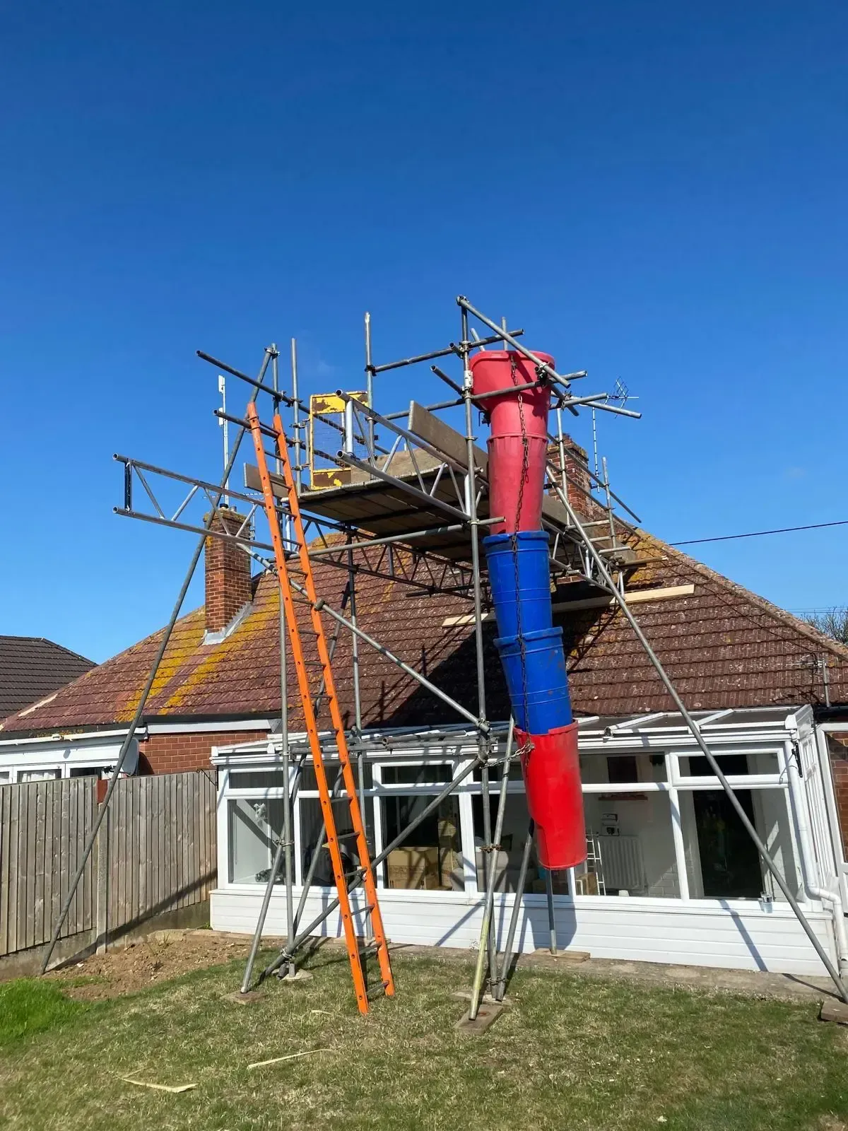 Scaffolding erected beside a chimney stack fitted with coloured cowl covers. Scaffolding erected beside a chimney stack fitted with coloured cowl covers.