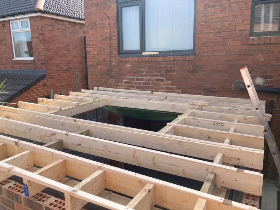 A timber roof extension frame being built on a brick house, the type of rear extension that commonly gets fitted with a green roof. A timber roof extension frame being built on a brick house, the type of rear extension that commonly gets fitted with a green roof.