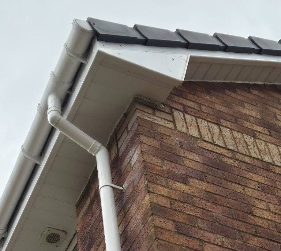 Close-up corner of white uPVC fascia board fitted over red brick.