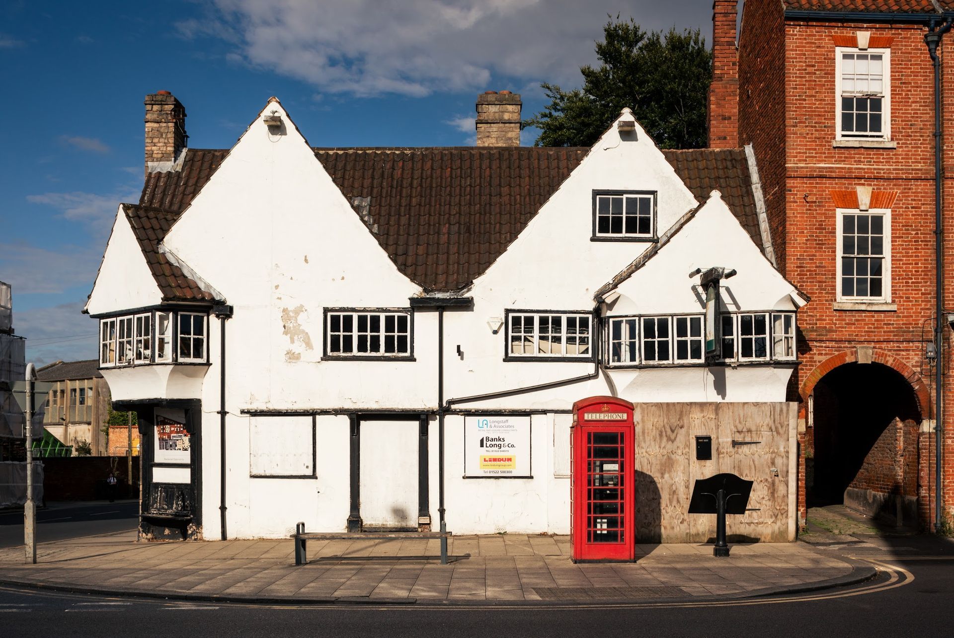 A white timber-framed period building beside a red phone box, typical of a Nottinghamshire conservation area.