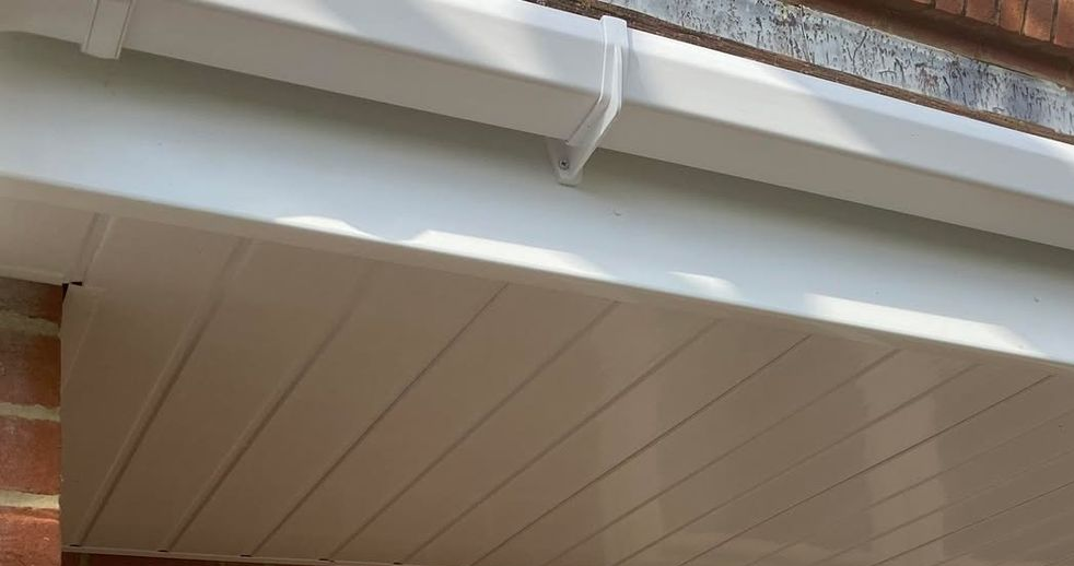 Close-up of white uPVC fascia and soffit boards fitted against a red brick wall.